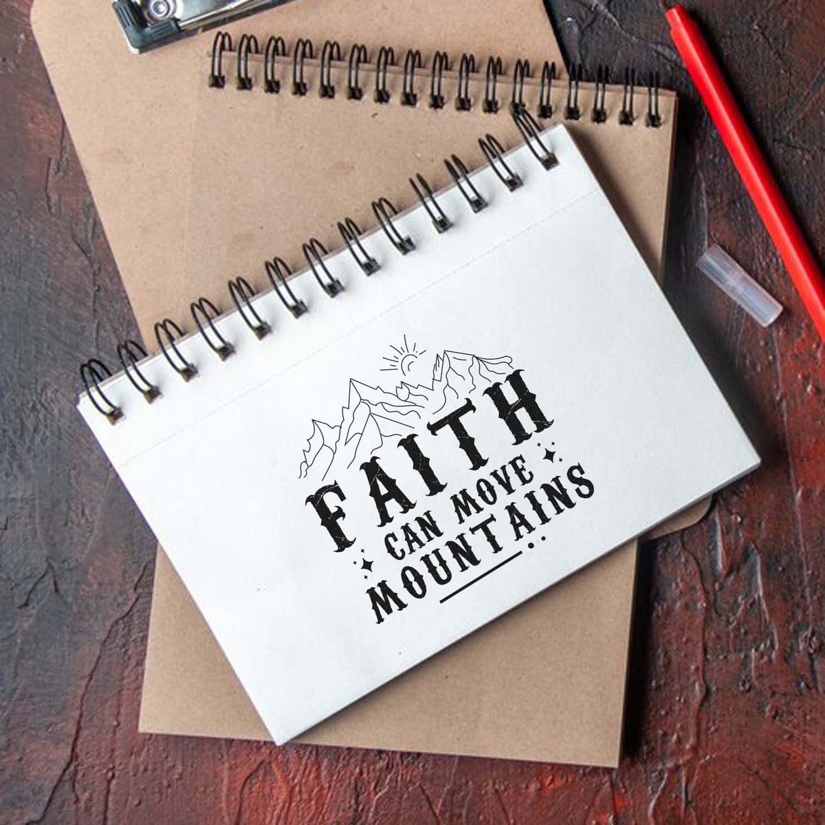Faith Can Move Mountains rubber stamp design on spiral notebook, featuring mountain graphic and inspirational Christian message.