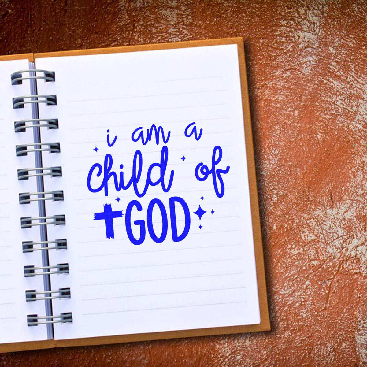 Inspirational rubber stamp design reading I am a child of God in blue on a notebook page.