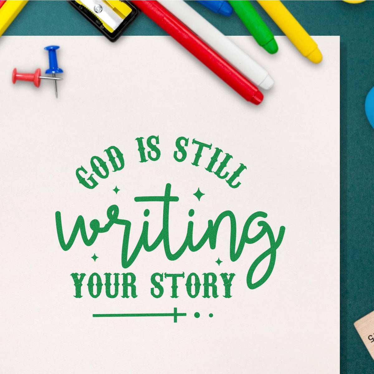 Christian rubber stamp design reading God is still writing your story in green on paper with colorful stationery.
