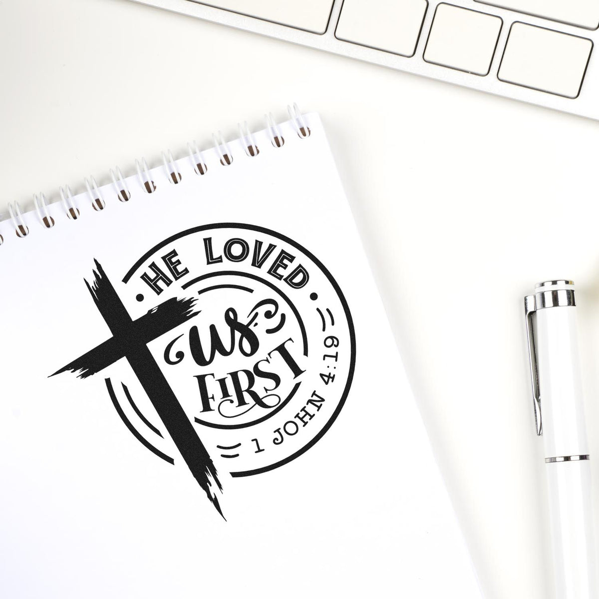 Christian rubber stamp with cross and He Loved Us First Bible verse, 1 John 4:19.