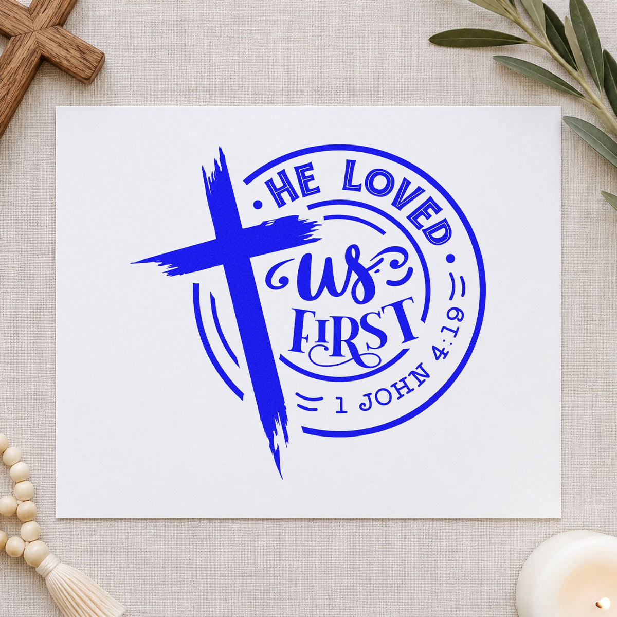 He Loved Us First Round craft stamp imprinted in blue ink on paper, a design suited to ornament crafts.