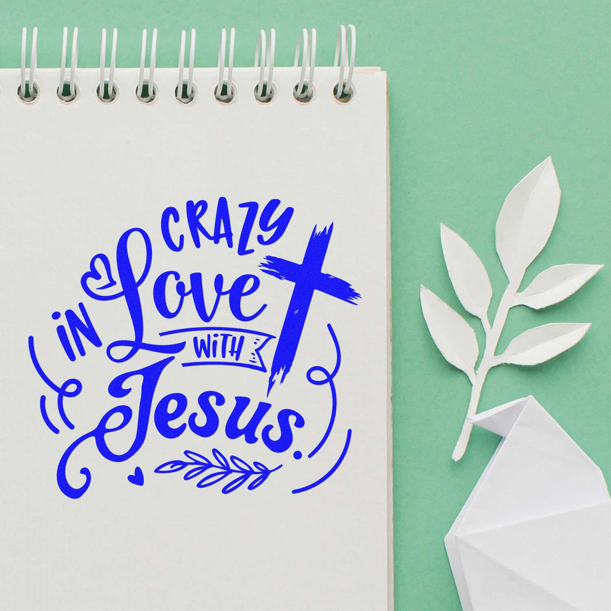Blue Christian rubber stamp impression reading Crazy in Love with Jesus on a notebook with cross and decorative flourishes.