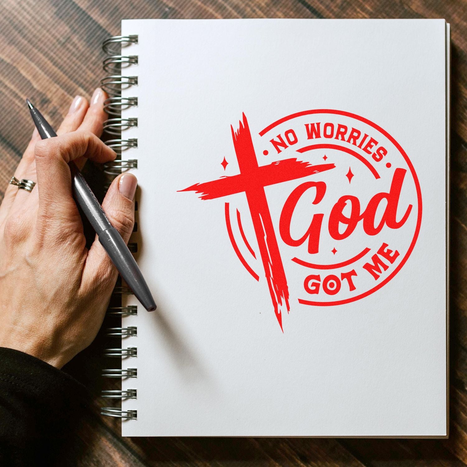 Custom Christian rubber stamp design reading No Worries, God Got Me stamped in red on a spiral notebook.
