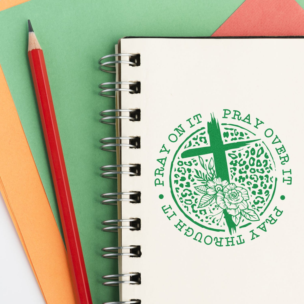 Custom Christian rubber stamp on a notebook reading Pray on it, pray over it, pray through it with cross and floral design.