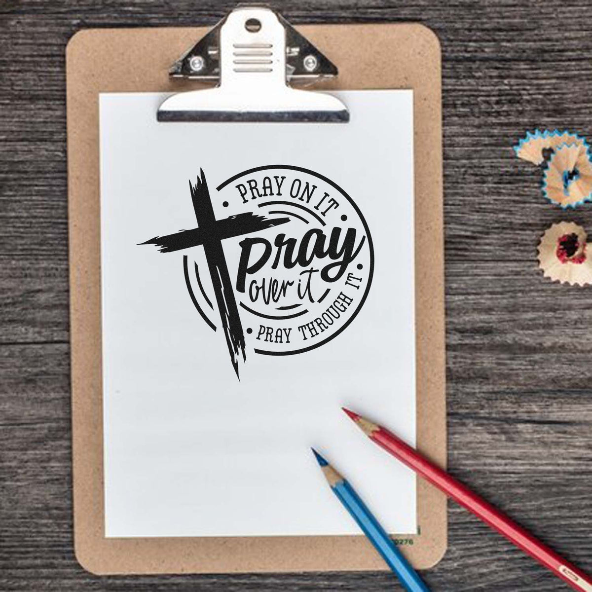 Christian rubber stamp with cross and Pray on it, pray over it, pray through it quote on clipboard.