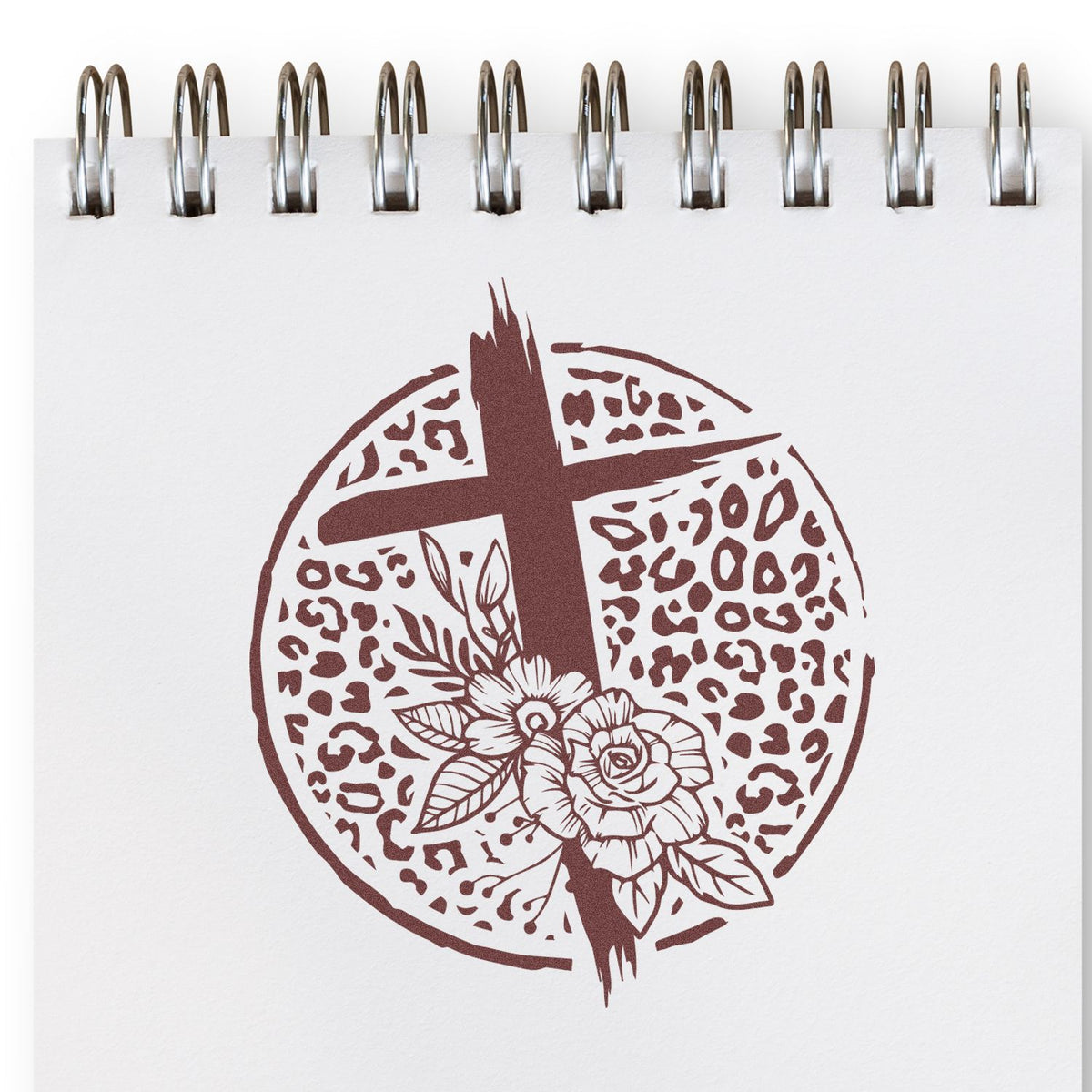 Decorative floral cross rubber stamp design with leopard print circle, stamped in a spiral notebook page.