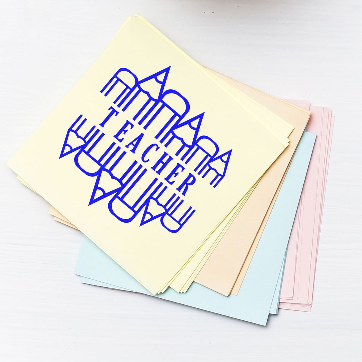 Teacher rubber stamp on pastel paper sheets for classroom grading, lesson prep, and school organization.