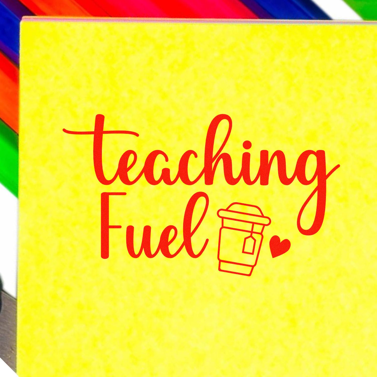 Teaching Fuel rubber stamp with red script text, coffee cup icon, and heart on a yellow background for teachers.