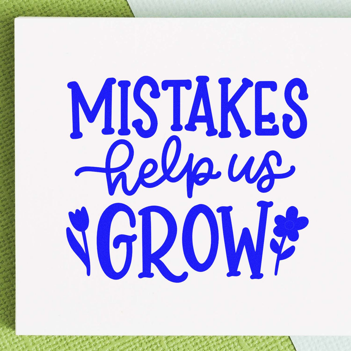Inspirational rubber stamp design with blue text reading Mistakes help us Grow and floral accents.