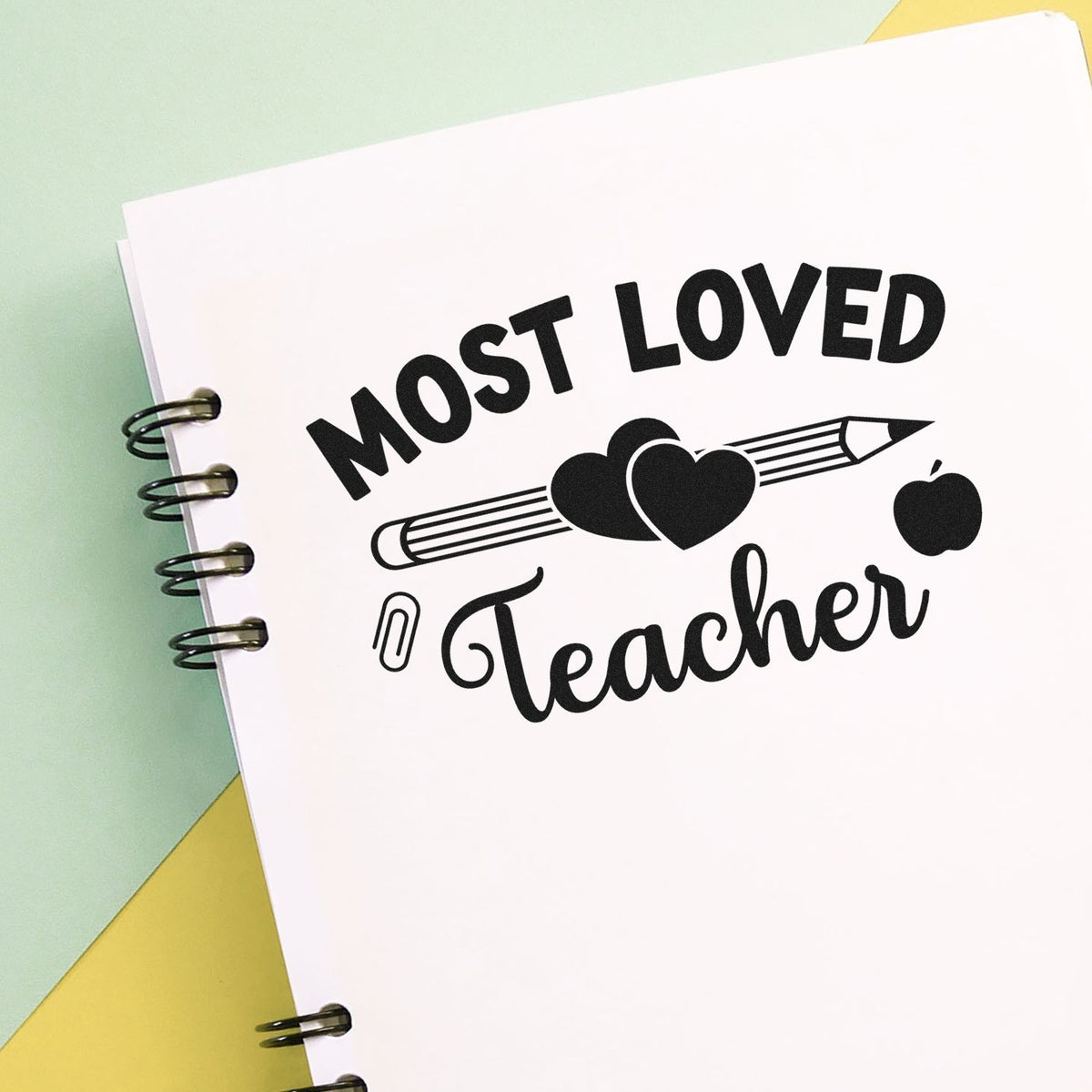 Most Loved Teacher rubber stamp design with pencil, heart, apple, and paperclip on notebook page.