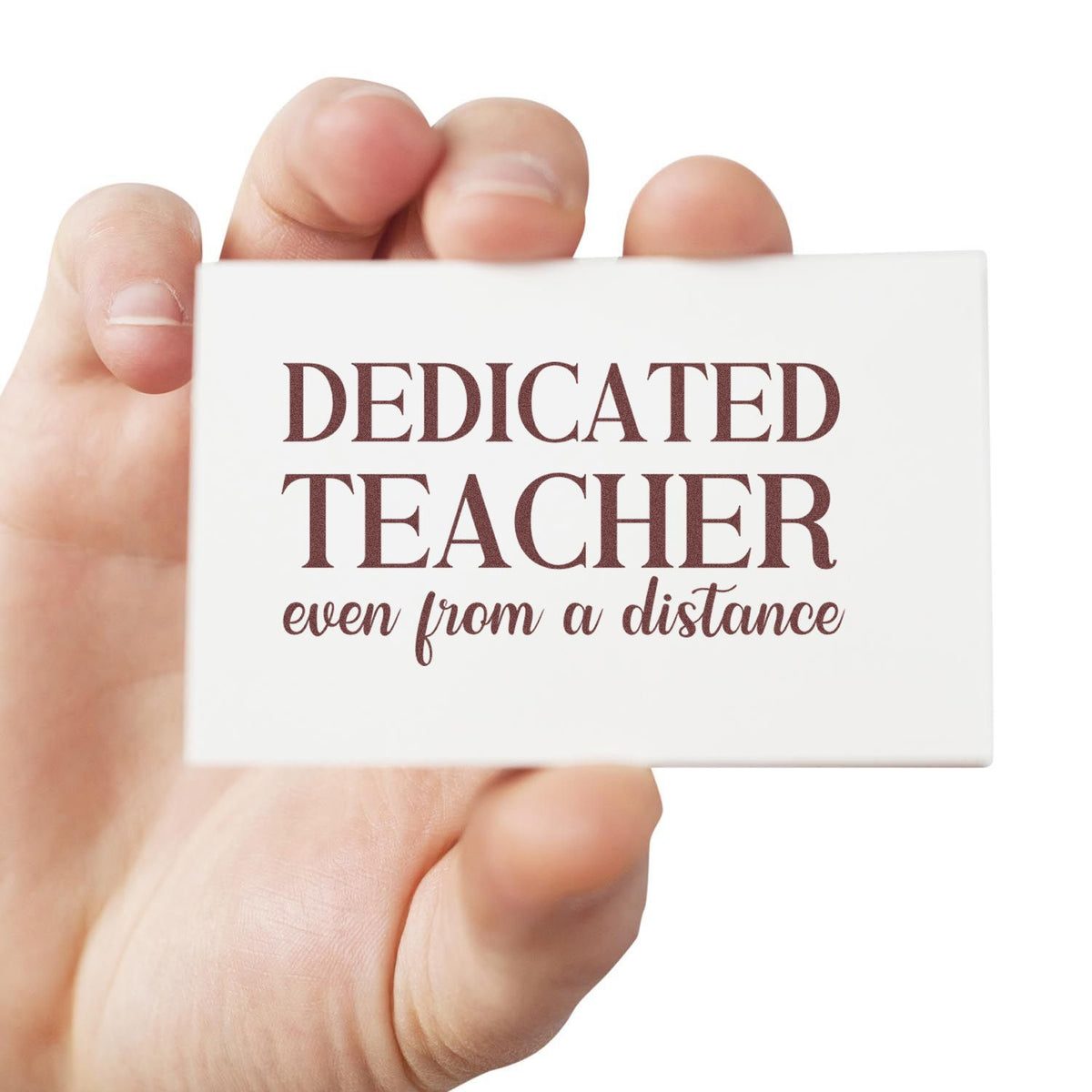 Hand holding a dedicated teacher rubber stamp with even from a distance message for teacher appreciation.