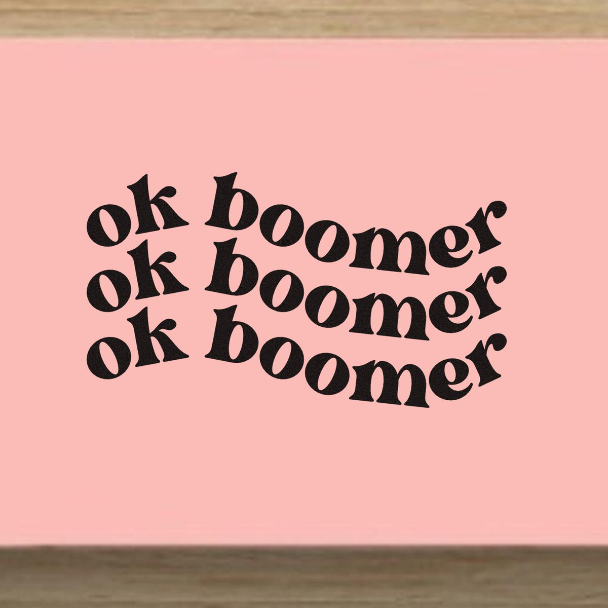 Repeated Wavy OK Boomer Pre-Inked Stamp – PSI imprint stamped in black ink. Three curved rows repeat the phrase “Ok Boomer” in bold serif lettering.