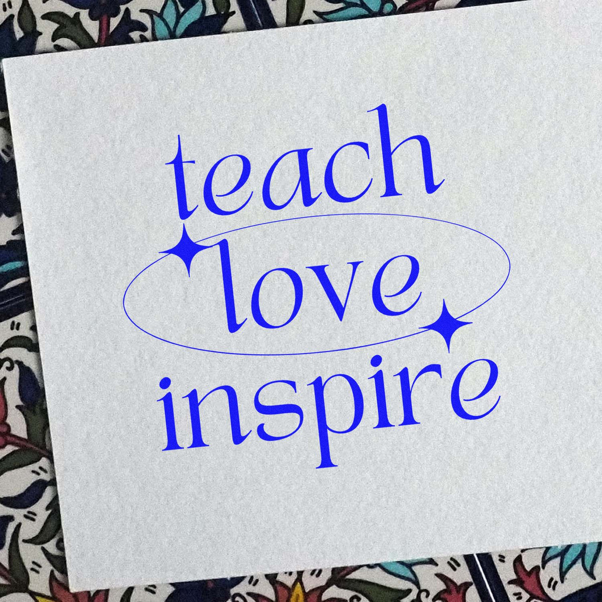Teach love inspire rubber stamp design in blue ink on paper with decorative oval and star accents.