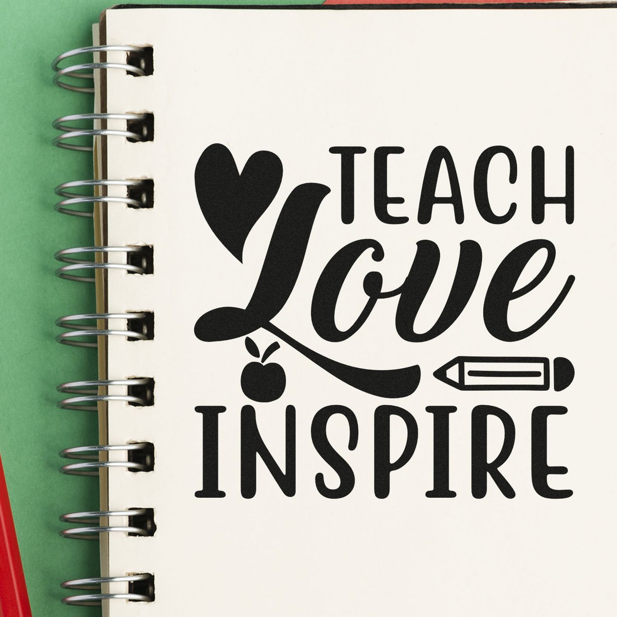 Teacher rubber stamp design with heart, apple and pencil reading Love Teach Inspire on a spiral notebook page.