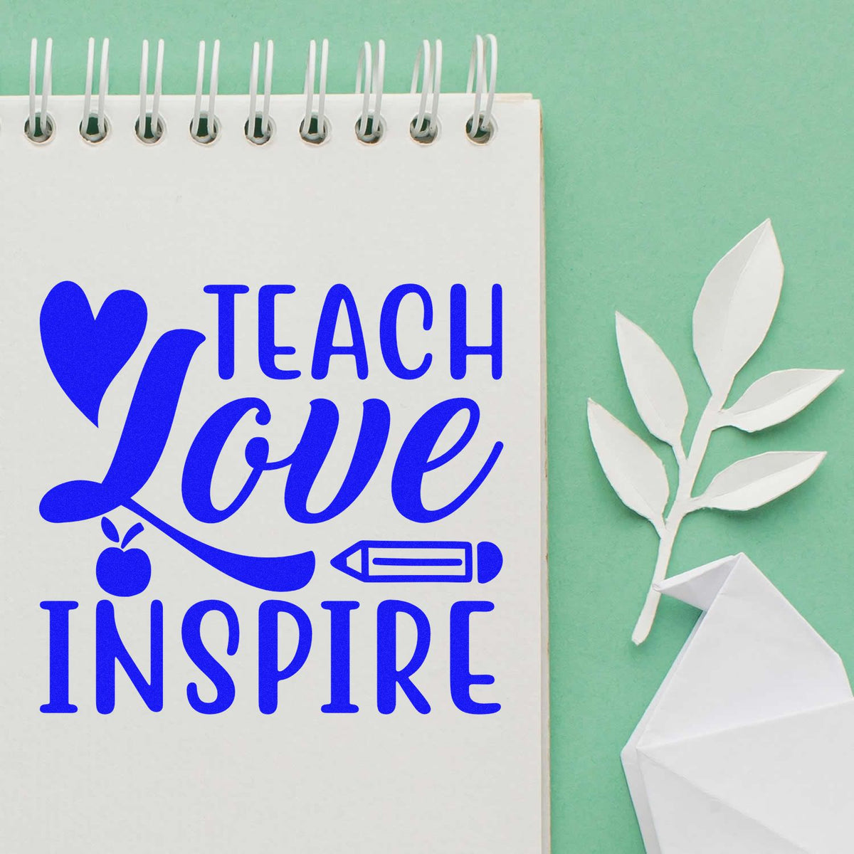 Teacher rubber stamp design reading Teach Love Inspire in blue on notebook, with heart, apple, and pencil icons.