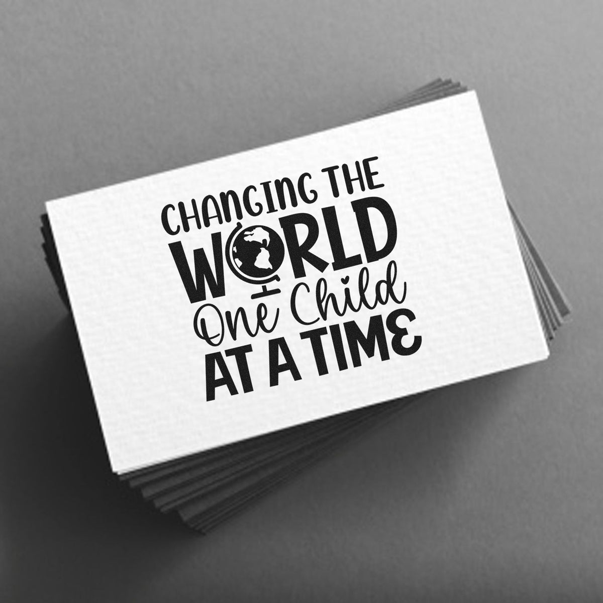 Changing The World One Child At A Time PSI Pre-Inked Stamp imprint stamped in black ink. “Changing the World One Child at a Time” incorporates a globe in “World.”