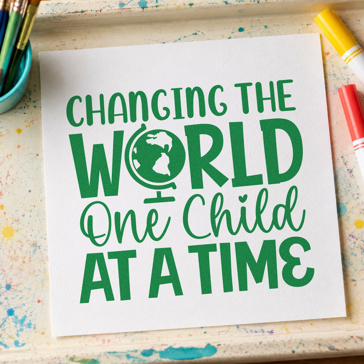 Changing World One Child craft stamp imprint in green ink on a handmade project, one idea being framed charity wall.