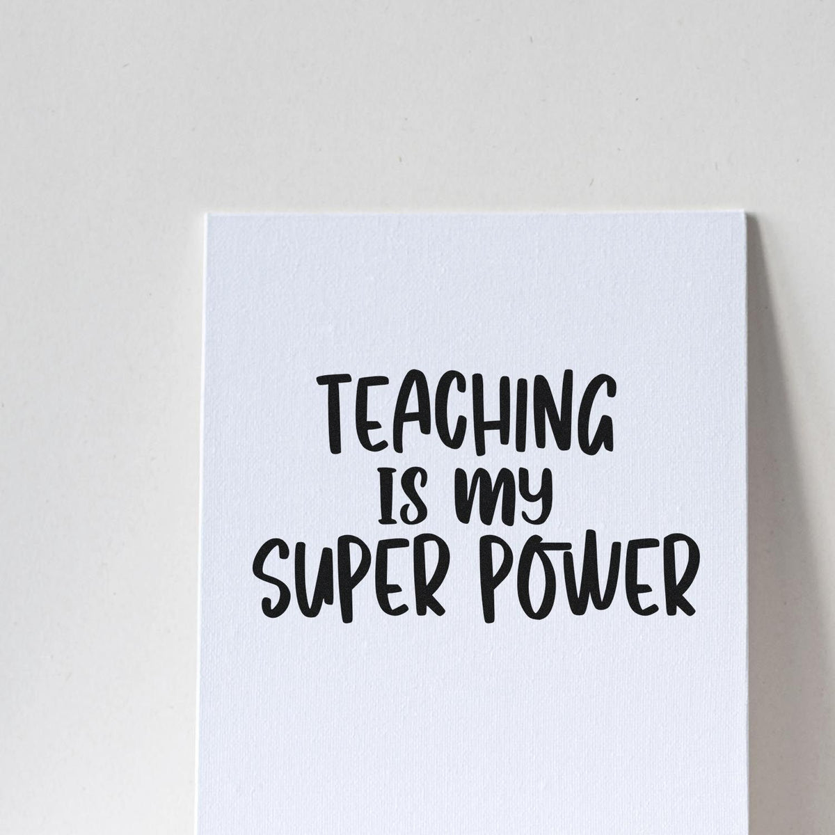 Teaching Is My Super Power Slim Pre-Inked Stamp imprint stamped in black ink. Four rows of hand-drawn capitals read “Teaching Is My Super Power.”