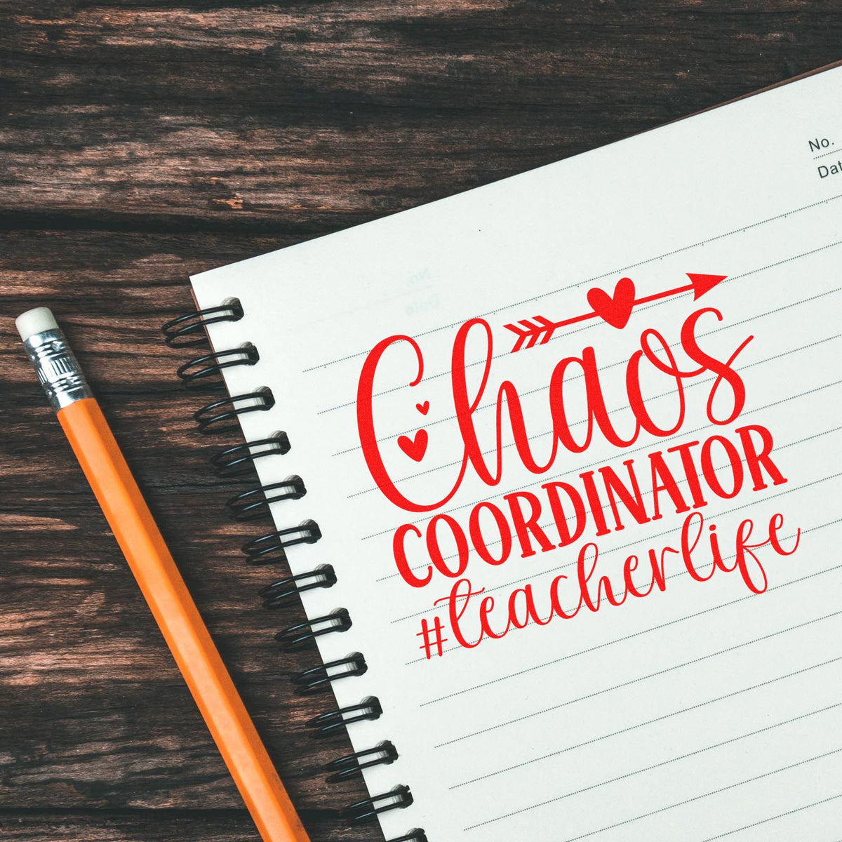 Teacher rubber stamp with red Chaos Coordinator #teacherlife message on a notebook beside a pencil.