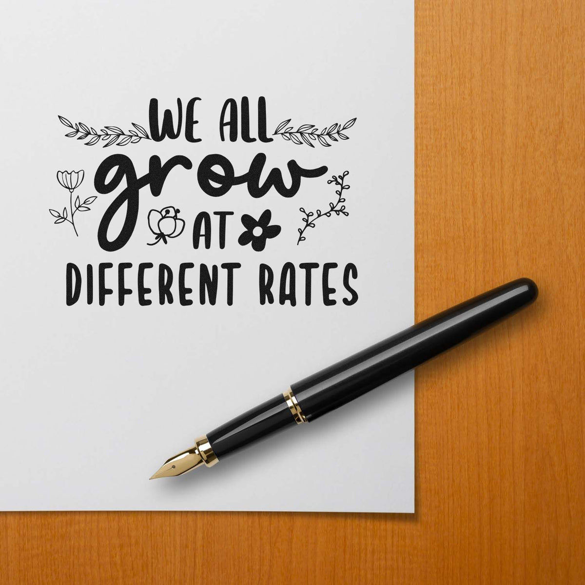 Inspirational quote rubber stamp reading We all grow at different rates with floral accents and fountain pen.