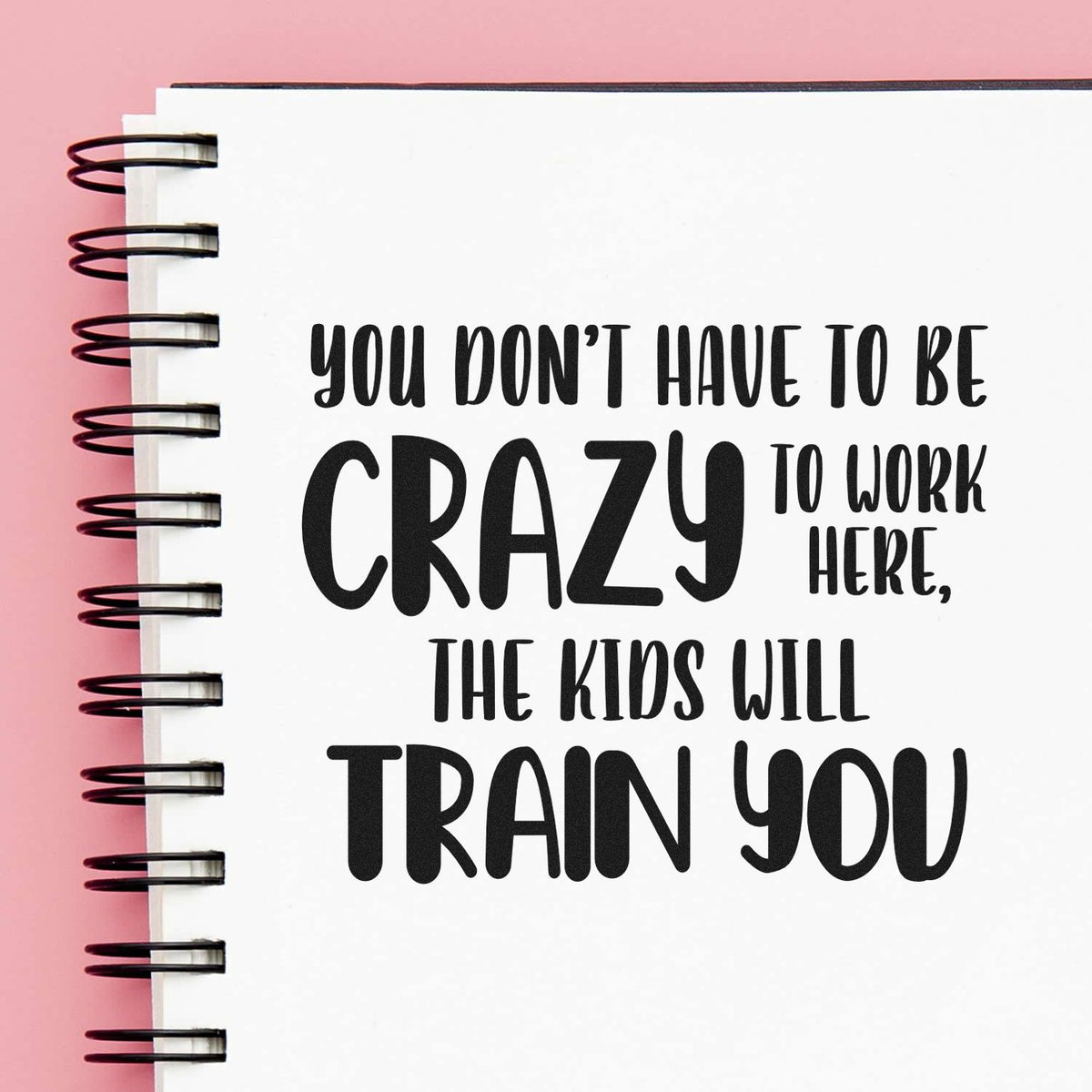 Slim Pre-Inked Crazy Kids Will Train You Stamp imprint stamped in black ink. “You Don't Have to Be Crazy to Work Here, the Kids Will Train You” uses varied bold lettering.