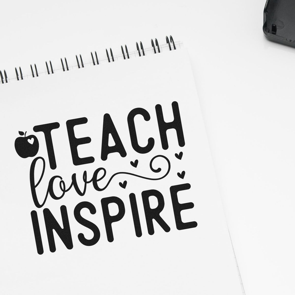 Teacher rubber stamp design with Teach, Love, Inspire on a notebook page, featuring bold lettering and heart accents.