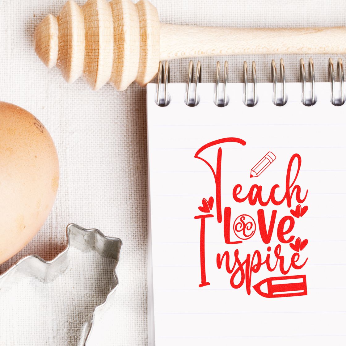 Teacher Love Inspire red rubber stamp design on notebook, ideal for classroom crafts, planners, and inspirational stamping.