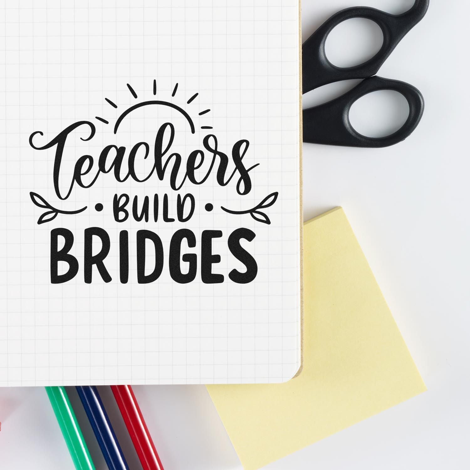 Teachers Build Bridges rubber stamp design for teacher appreciation crafts, with notebook, pens, scissors, and sticky note.