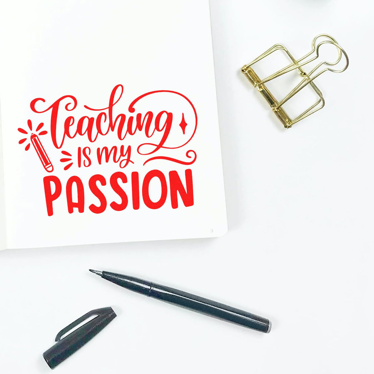 Teacher rubber stamp design with Teaching is my passion in red on a notebook, with pen and binder clip.