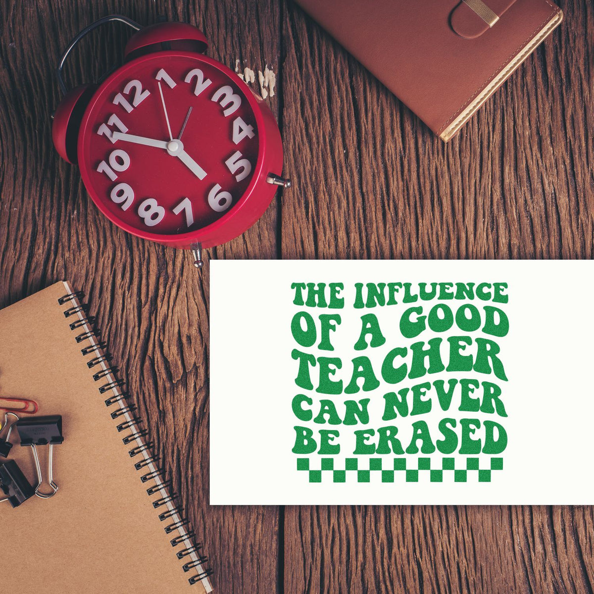 Inspirational teacher rubber stamp with quote, The influence of a good teacher can never be erased, on a rustic desk.