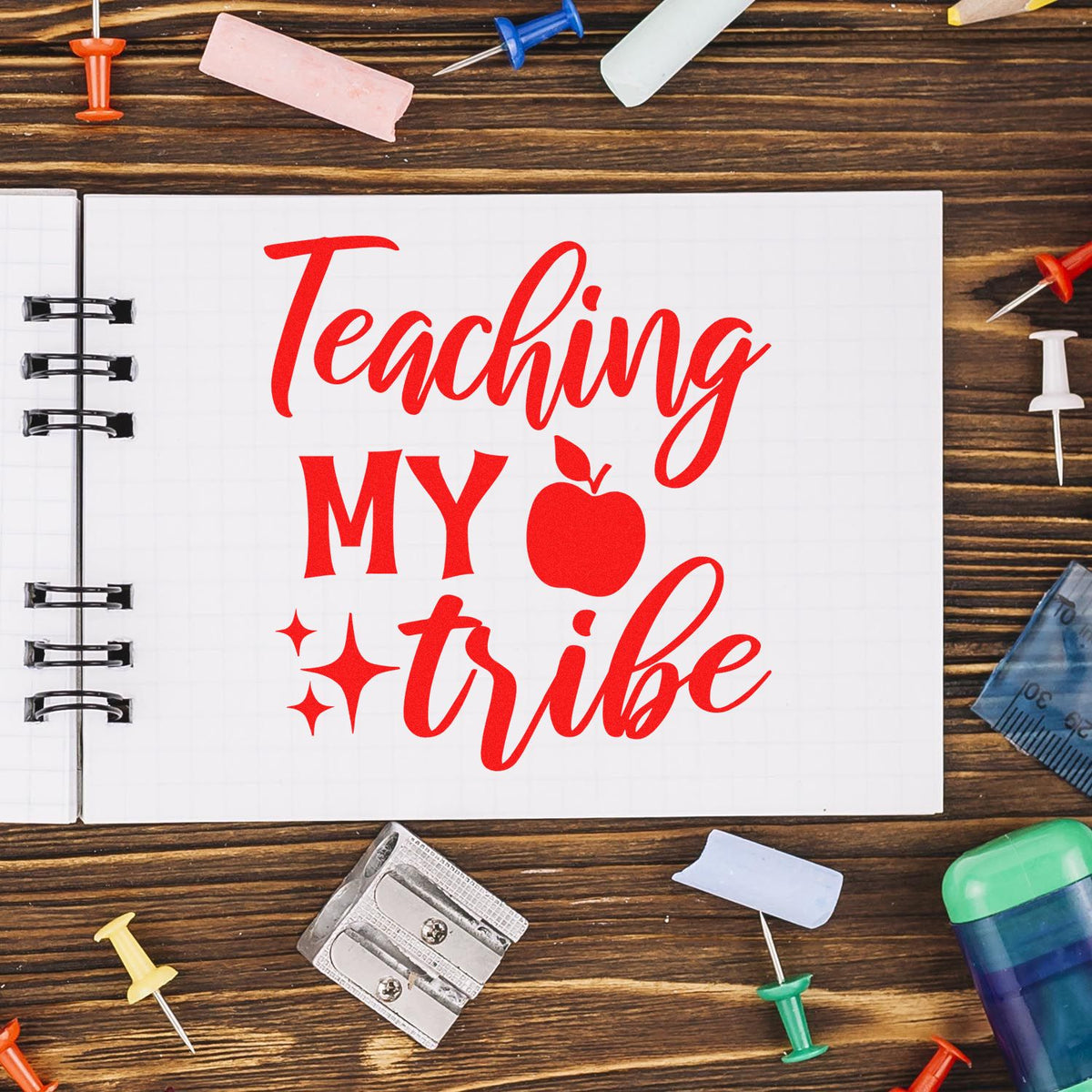Teaching My Tribe rubber stamp design for teachers, shown in red on a notebook with school supplies.
