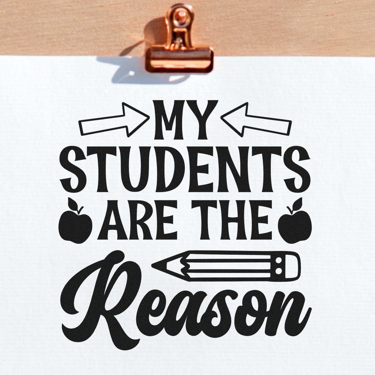 Teacher rubber stamp design reading My Students Are the Reason with arrows, apples, and pencil on paper.