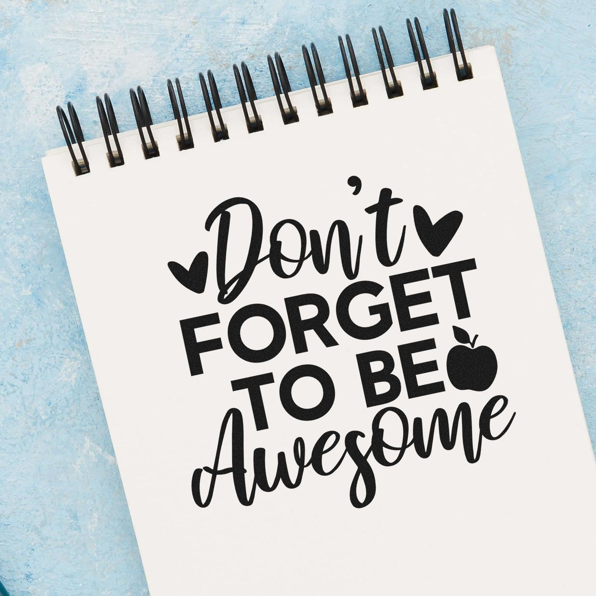 Motivational rubber stamp design with Dont Forget to Be Awesome text, hearts, and apple icon on a notebook page.
