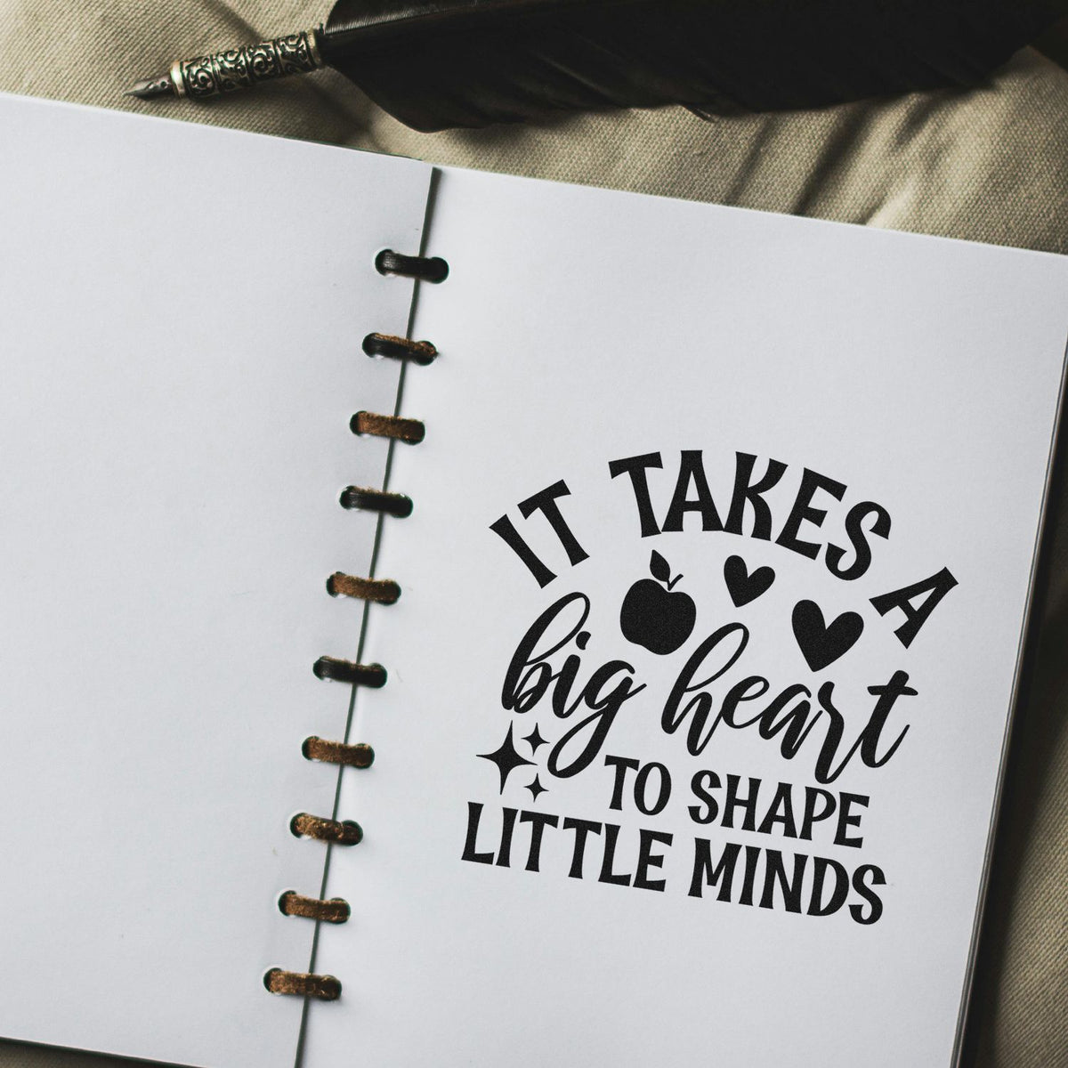 Teacher rubber stamp impression reading It takes a big heart to shape little minds on an open notebook.