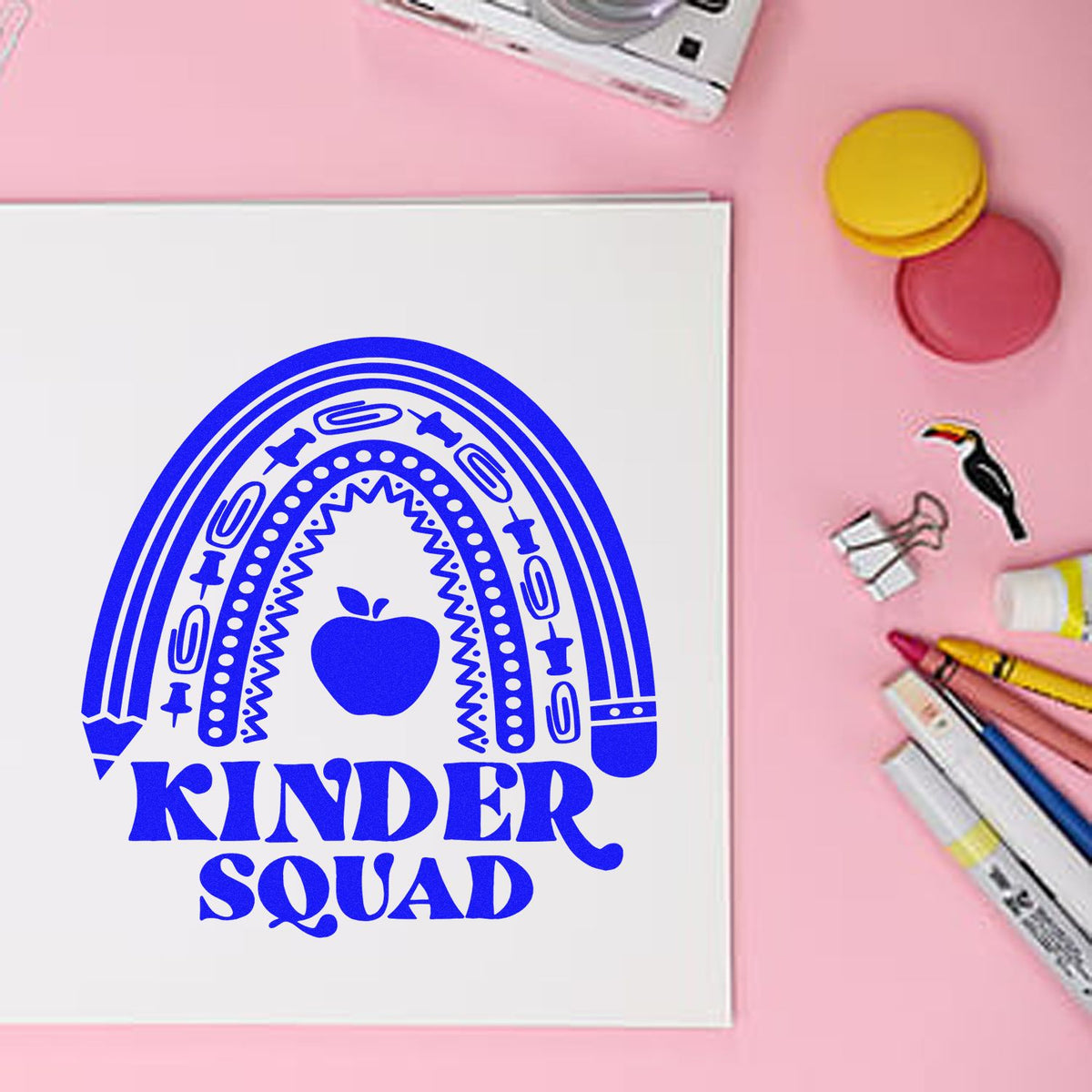Custom Kinder Squad rubber stamp design with rainbow apple logo, ideal for classroom crafts and teacher stationery.