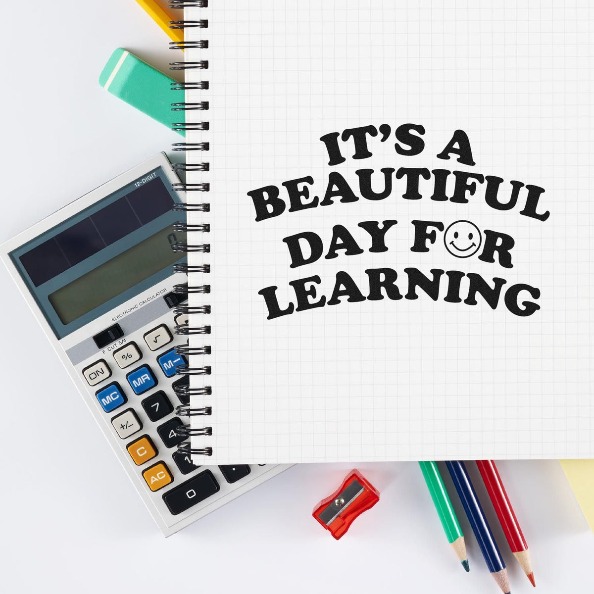 Teacher rubber stamp design reading Its a beautiful day for learning on notebook with school supplies.