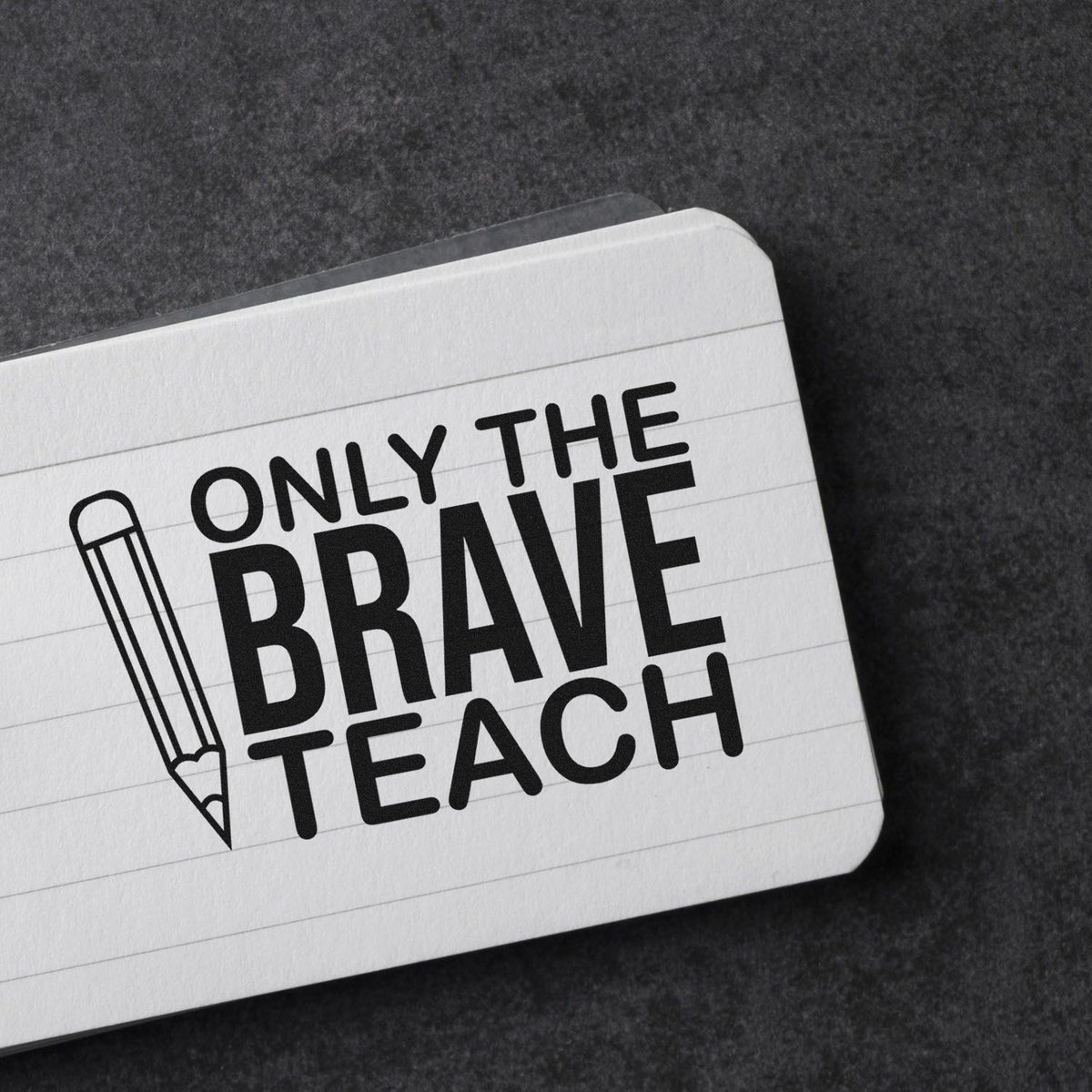 Teacher rubber stamp design reading Only the Brave Teach with pencil icon on notebook paper.