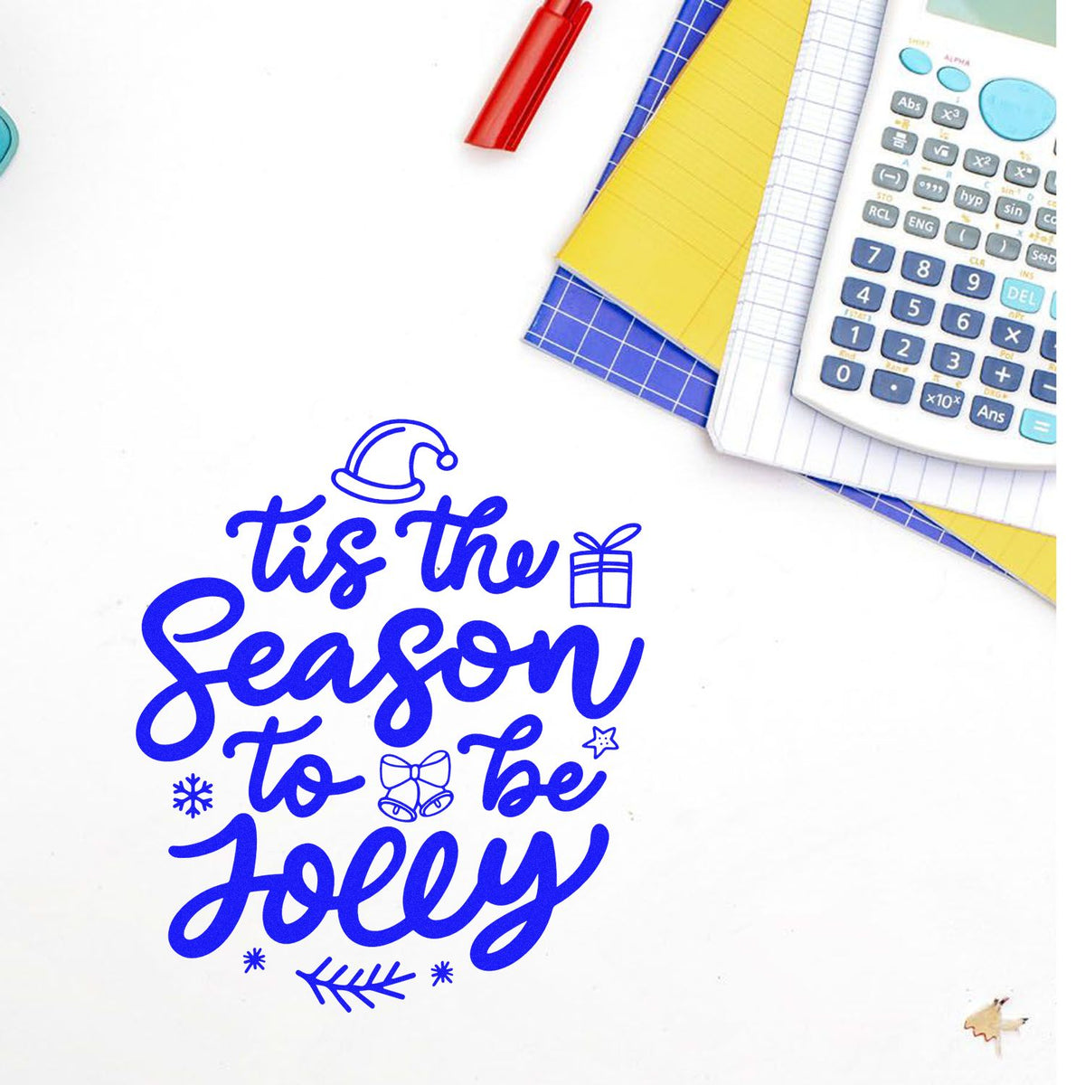 Christmas rubber stamp design with Tis the Season to Be Jolly in blue, shown on a stationery flat lay.