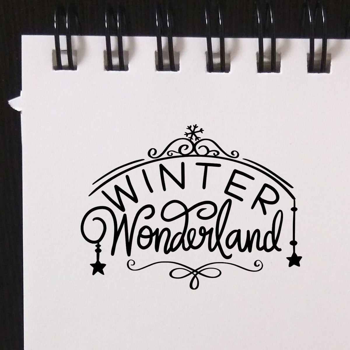 Winter Wonderland decorative rubber stamp design with snowflake and script lettering on notebook paper.