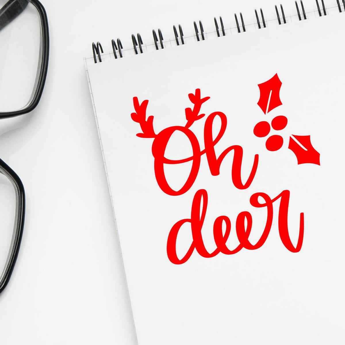 Red Oh Deer Christmas rubber stamp design with antlers and holly on notebook page, perfect for holiday cards and crafts.