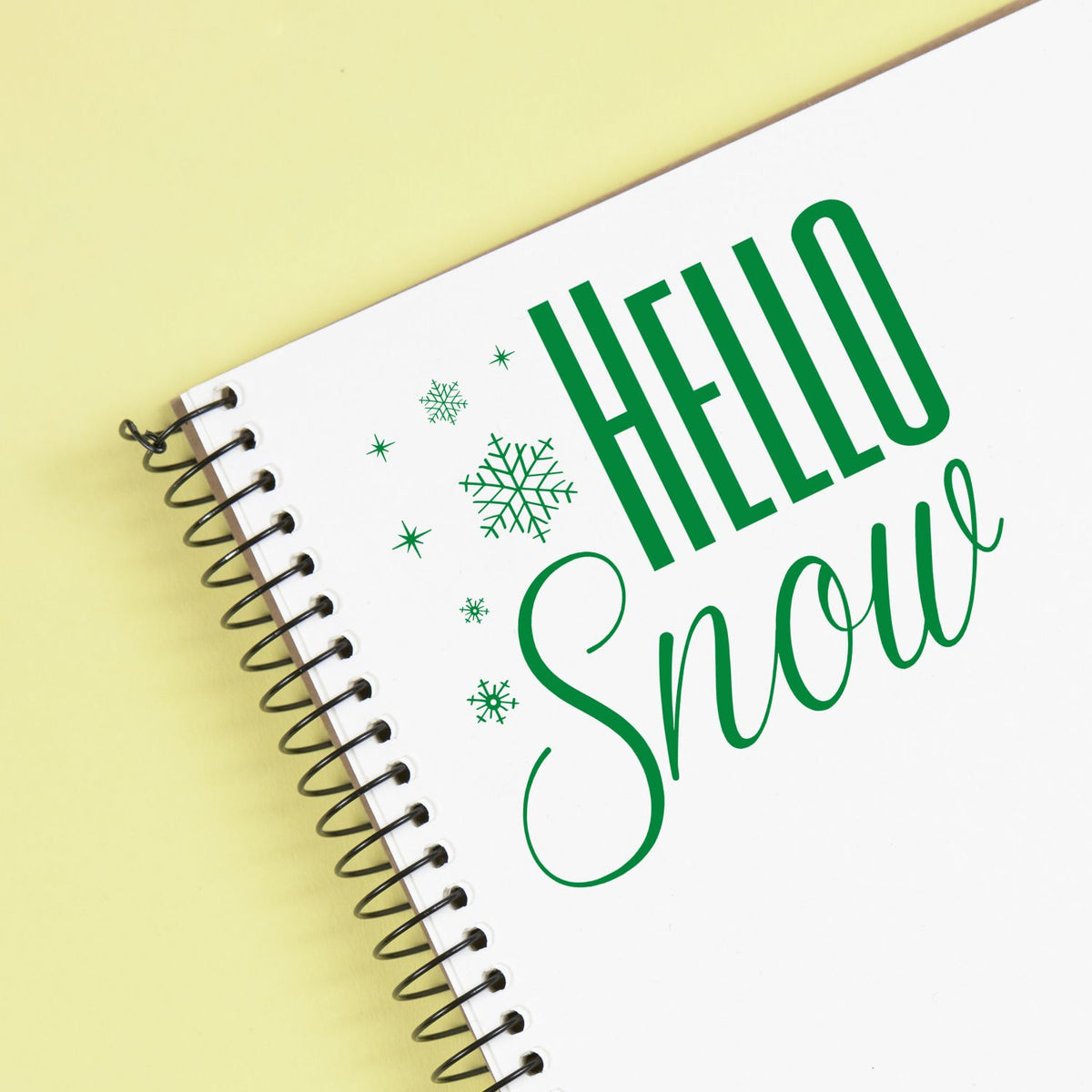 Green Hello Snow rubber stamp design on spiral notebook with snowflakes for winter greeting cards and craft projects