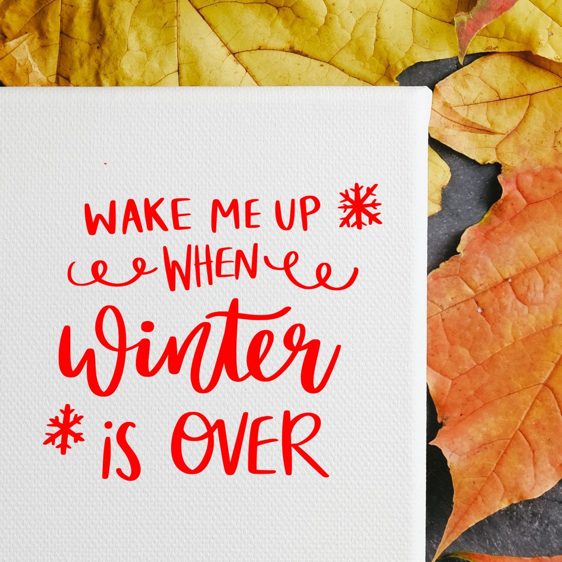 Seasonal rubber stamp design with Wake Me Up When Winter Is Over quote in red on a white card with autumn leaves.