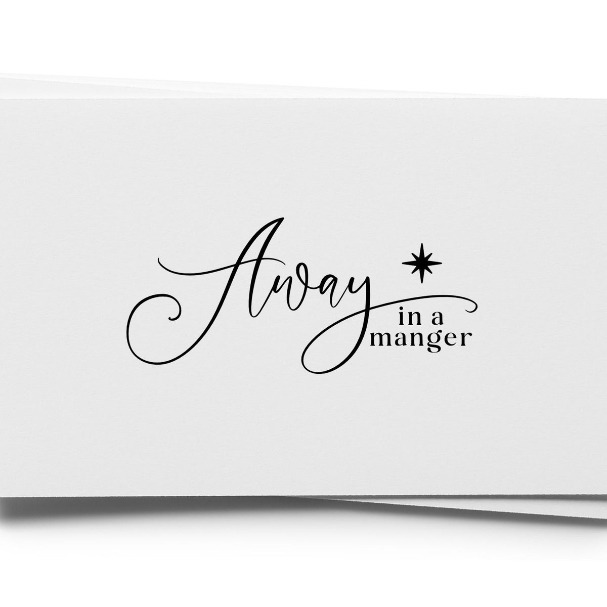 Away In A Manger Slim Pre-Inked Stamp imprint stamped in black ink. Sweeping script “Away” joins smaller “In a Manger” beside a shining star.
