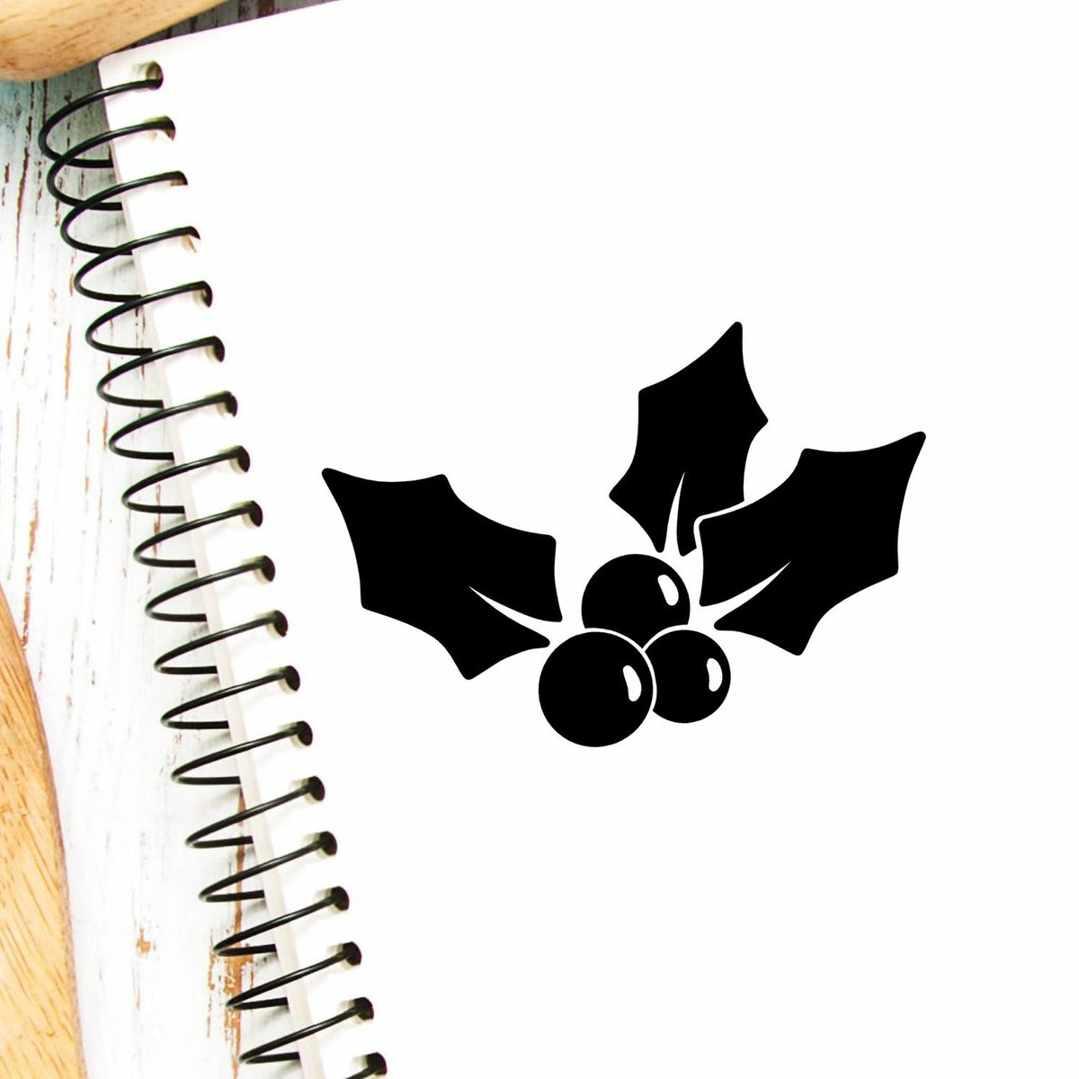Holly berry rubber stamp design on a notebook page, perfect for Christmas crafts, card making, and holiday scrapbook projects.