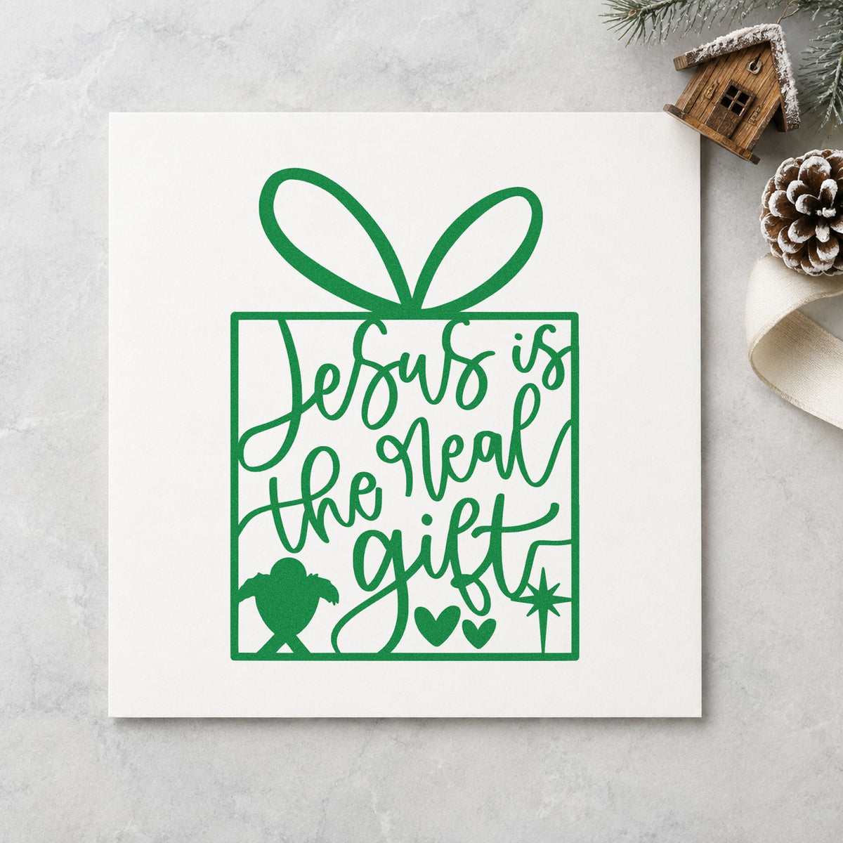 Jesus Is The Real Gift craft stamp imprinted in green ink on paper, a design suited to framed sunday room.
