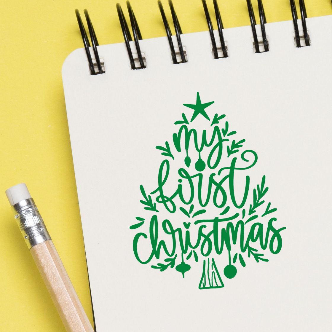 Green My First Christmas tree rubber stamp design on notebook paper with pencil, ideal for holiday cards and scrapbook crafts.
