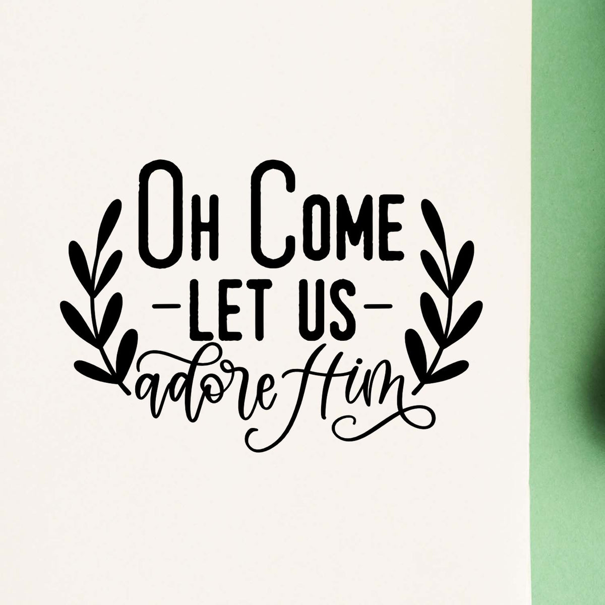 Oh Come Let Us Adore Him Compact Pre-Inked Stamp – Slim imprint stamped in black ink. “Oh Come Let Us Adore Him” is framed by two leafy branches.