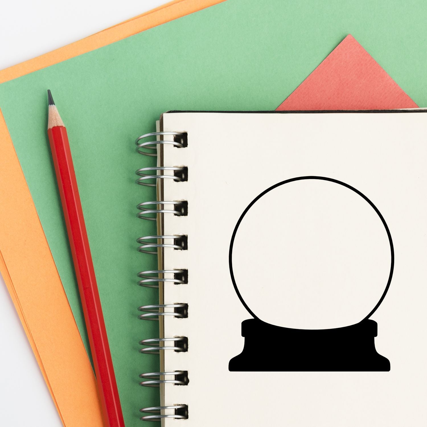 Blank rubber stamp mockup on a spiral notebook with pencil and colored paper for custom branding and craft projects.