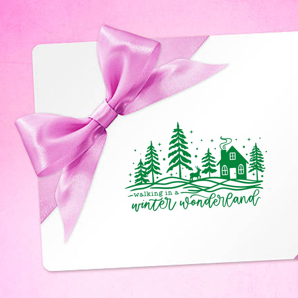 Holiday card with pink ribbon and green winter wonderland rubber stamp featuring trees, cabin and deer
