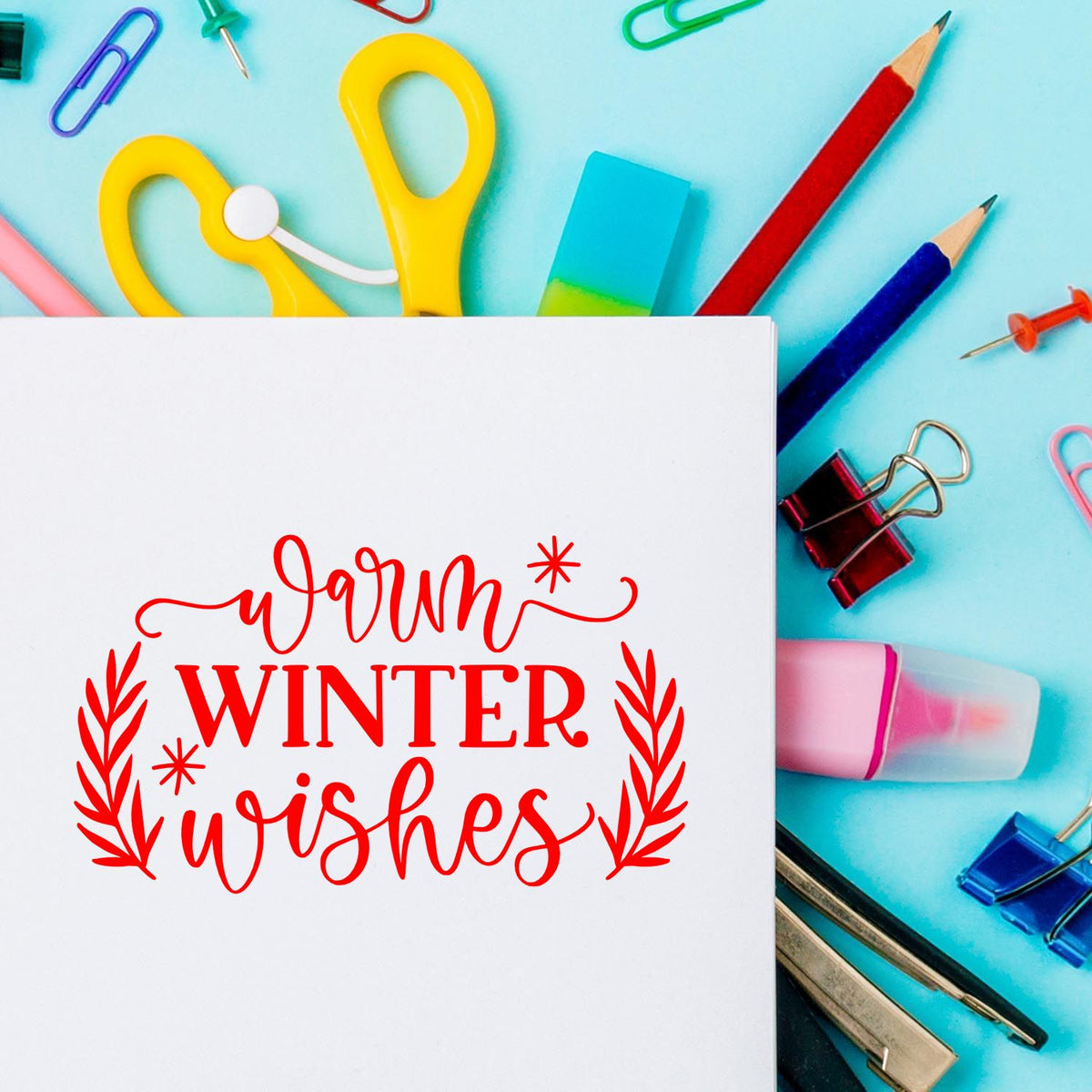 Warm Winter Wishes rubber stamp design on white card, surrounded by colorful stationery and craft supplies.